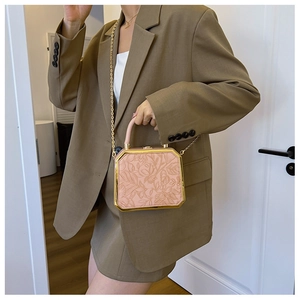 Detail of pink box bag with floral relief and gold chain strap on coffee blazer