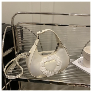 Detail of white lace heart pattern on half-moon handbag with adjustable shoulder strap