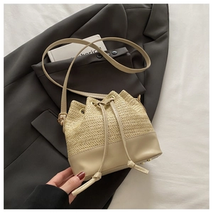 Detailed close-up of straw bucket bag with leather base and drawstring closure