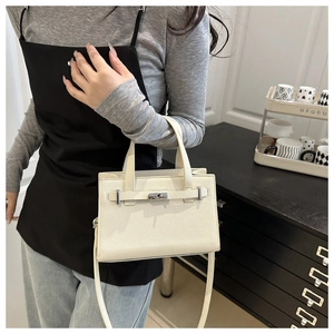 Detail of the cream textured leather handbag with a metal buckle and long shoulder strap