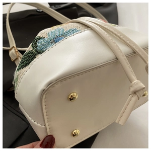 Close-up of ethnic bucket bag with floral embroidery and golden base studs