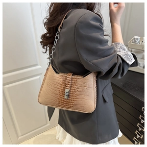 Detail of beige crocodile pattern handbag with silver metal twist lock and chain strap