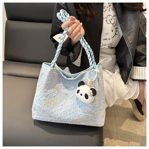 Detail of light blue cloud-textured handbag with braided handle and flower panda charm