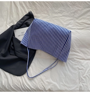 Close-up of blue and white striped canvas tote bag with slim shoulder strap design