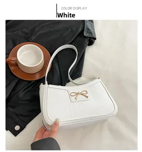 Detailed view of white crocodile pattern shoulder bag with a gold bow buckle