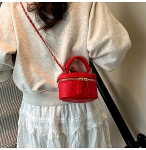 Detail of red quilted mini square bag with chain strap worn by model in casual setting