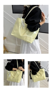 Detail of cream tote bag featuring elegant white lace pearl bow charm and glossy finish