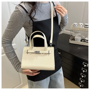 Detail view of cream lychee texture crossbody bag with silver rotating clasp and strap