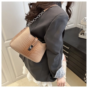 Detail of caramel crocodile pattern shoulder bag with silver chain strap and flap closure