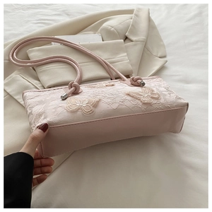 Detail of pink lace texture and 3D butterfly appliqué on the women's shoulder tote bag