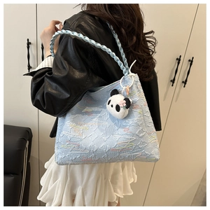 Detail of light blue bubble textured tote bag with panda pendant and woven handle