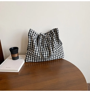 Detailed view of large black and white gingham tote bag on a rustic wooden table