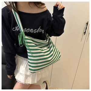 Detail of green and white striped canvas tote bag featuring decorative green lace bow accent
