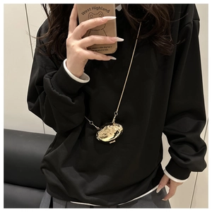 Détail d'un mini sac collier doré en forme de coquillage avec chaîne métallique