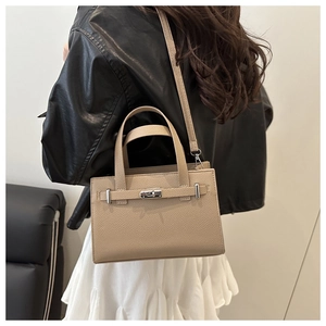 Detail of beige lychee pattern leather handbag with silver twist lock and crossbody strap