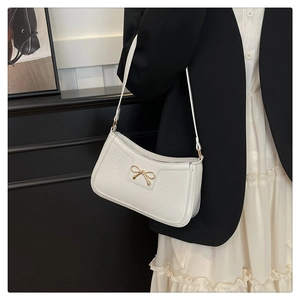 Detail showing the white crocodile pattern texture and golden bow on the shoulder bag