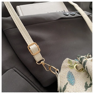 Macro shot of ethnic jacquard bucket bag showing gold hardware and turquoise floral pattern