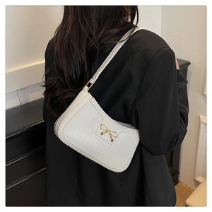 Detail of white crocodile texture underarm bag with a golden bow metal buckle