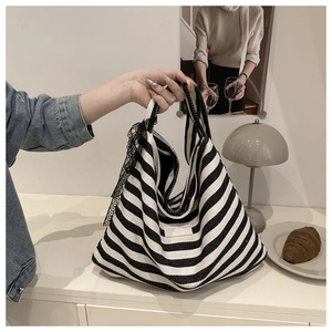 Detail of canvas tote bag with black and white stripes and a side lace bow accent