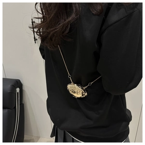 Vue détaillée du mini sac doré en forme de coquillage avec texture martelée et chaîne