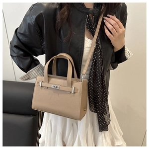 Detail of khaki pebbled leather handbag with metal turn-lock and detachable strap