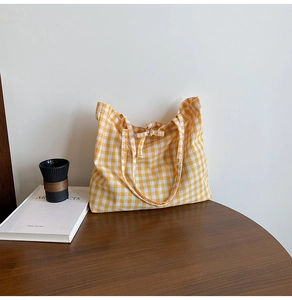 Detail of yellow gingham tote bag featuring a decorative bow tie and soft cotton fabric