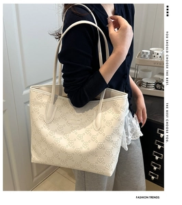 Elegant white tote bag with embossed flower patterns shown being worn by a model.