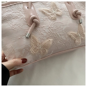 Detail of pink lace tote bag featuring 3D butterfly appliques and knotted leather handle