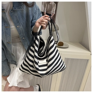 Detail view of a striped canvas tote bag featuring unique black lace trim on the side