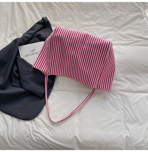 Detail shot of red and white striped canvas tote bag on minimalist fabric background