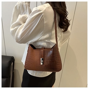 Detail of dark brown crocodile-patterned bag with silver metal twist lock and PU texture