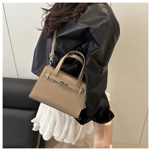 Detailed close-up of khaki lychee grain leather handbag with silver metallic turn-lock closure