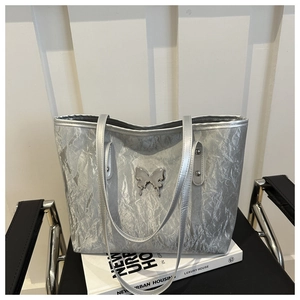 Detail view of silver tote bag featuring crinkled texture fabric and butterfly charm