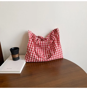Close-up of red and white plaid tote bag featuring a decorative ribbon bow tie detail