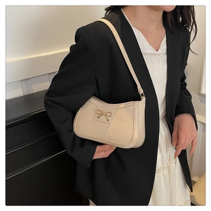 Détail d'un sac porté épaule beige à texture crocodile et boucle nœud doré chic