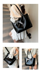 Close-up of black glossy PU leather tote bag with lace and pearl bow charm detail