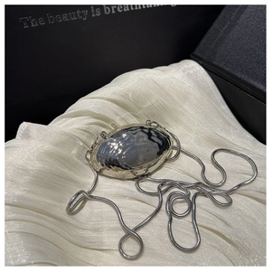 Macro view of silver metallic shell bag with textured ripples and sleek snake chain strap