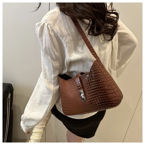 Detailed view of brown crocodile texture shoulder bag with metallic buckle on a model