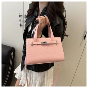 Detail of pink lychee leather handbag featuring silver metal twist lock and sleek handle