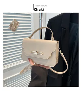 Detail view of khaki crossbody bag with gold chain buckle and top handle in lifestyle setting