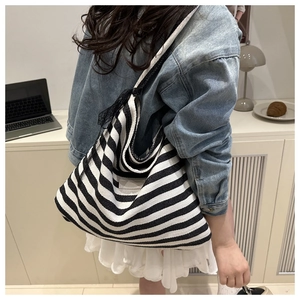 Detailed view of black and white striped canvas tote bag worn by a model in daily life