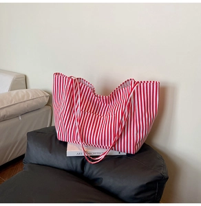 Detail of red and white striped canvas tote bag with front pocket on minimalist background