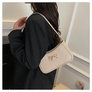 Détail d'un sac à bandoulière en cuir de crocodile crème avec boucle de nœud dorée