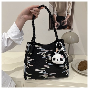 Detail of black tote bag with colorful wave embroidery and cute panda plush charm