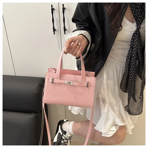 Detail of pink lychee leather handbag featuring silver twist lock and slim shoulder strap