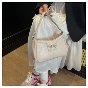 Gros plan du sac beige à motif crocodile avec un fermoir nœud en métal doré