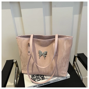 Detailed view of pink tote bag with pleated texture and silver butterfly logo ornament