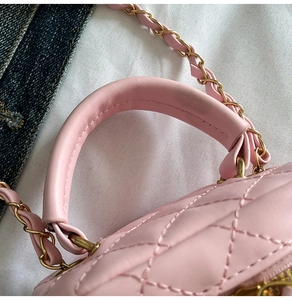 Close-up of quilted lattice leather texture with metal chain strap and round handle