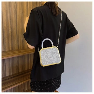 Detail of floral embossed light grey clutch bag with gold frame and chain strap