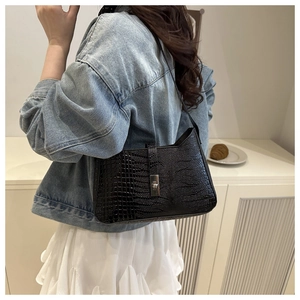 Detail of black crocodile texture shoulder bag with silver rectangular metal lock